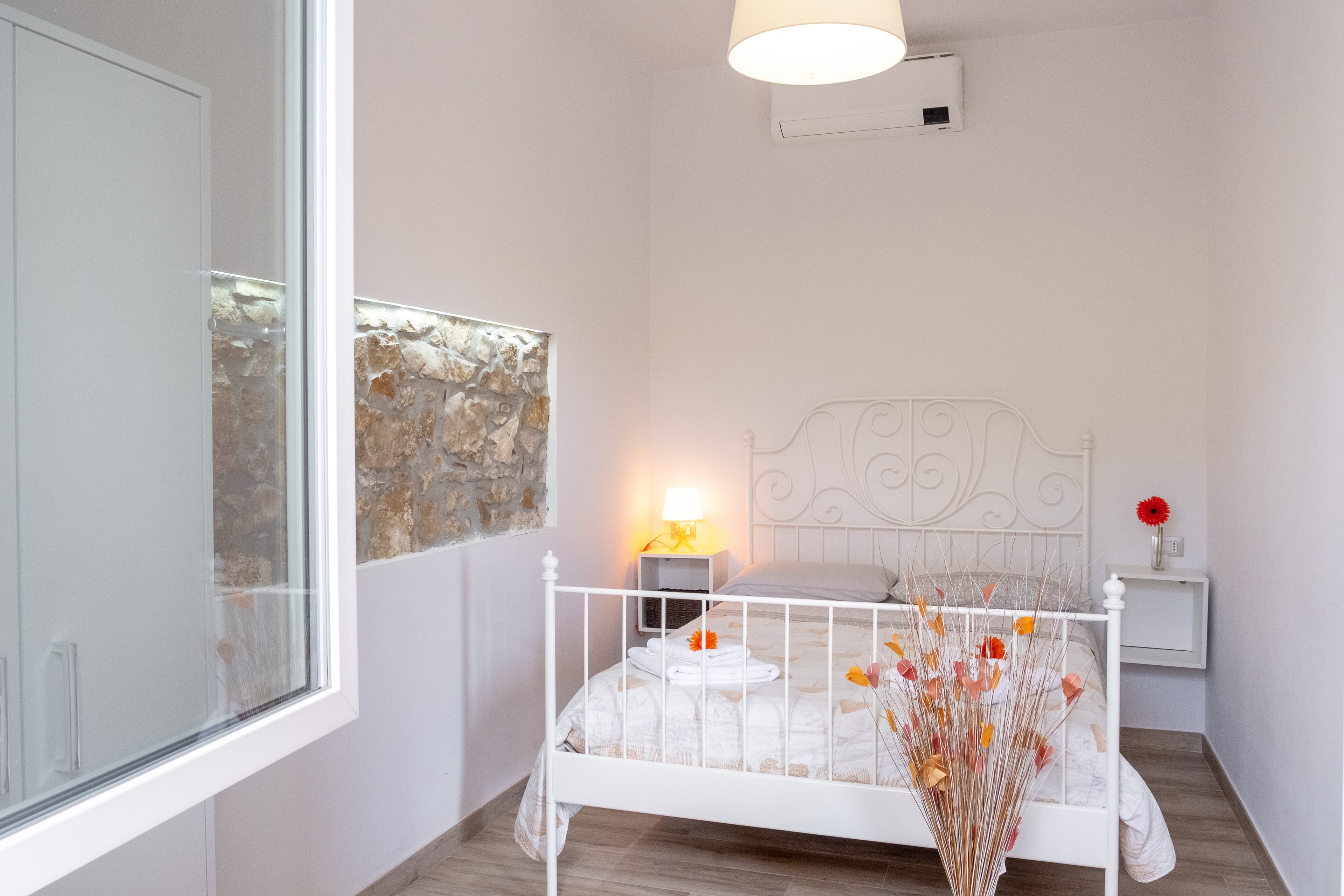 Camera matrimoniale — Un ambiente intimo e luminoso, con parete in pietra a vista e dettagli che trasmettono calore